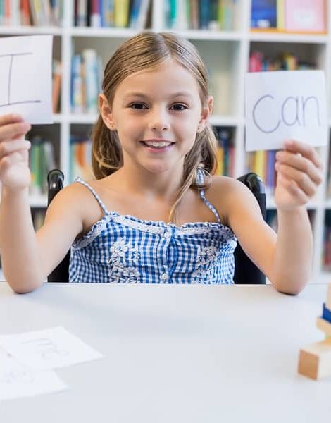 Disabled girl holding placard that reads I Can in library at school