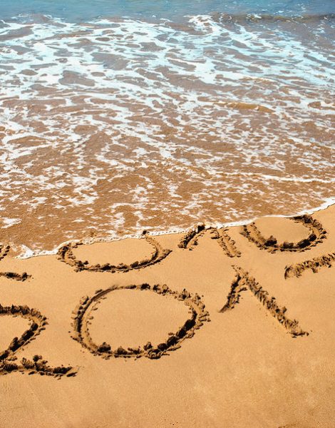 New Year 2017 is coming concept - inscription 2017 and 2016 on a beach sand the wave is covering digits 2016. New Year 2017 celebration on New Year tropical island travel tour.