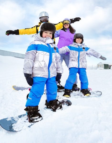Happy family of mother, father and two songs snowboarders having fun at ski resort