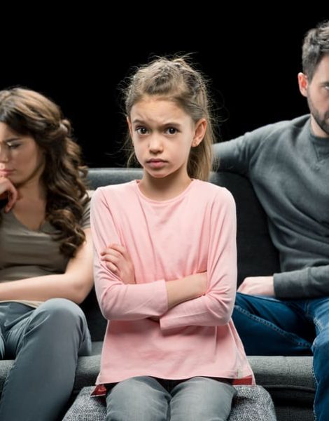 portrait of skeptical daughter and pensive parents behind on black divorce concept