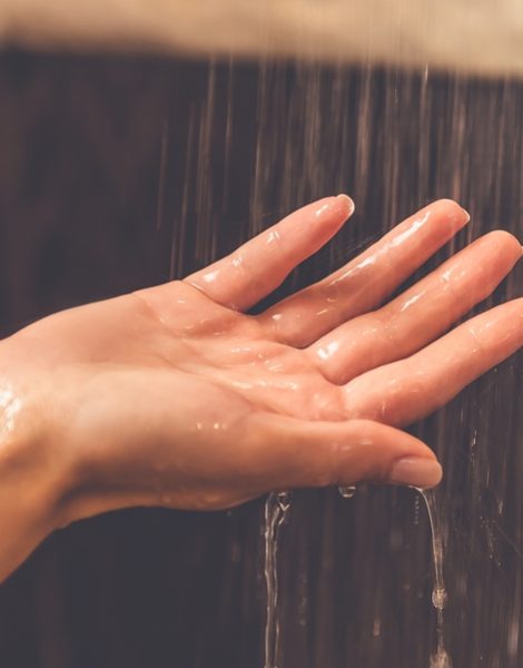 Beautiful hand of young woman taking shower in bathroom
