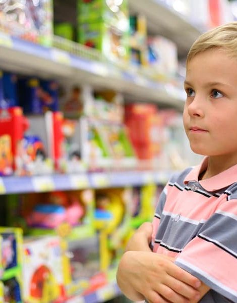 Boy looks at shelves with toys in shop