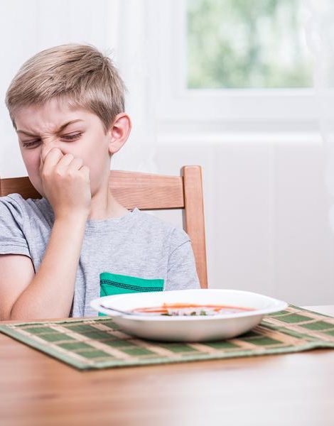 Child sitting at the table and refusing to eat soup
