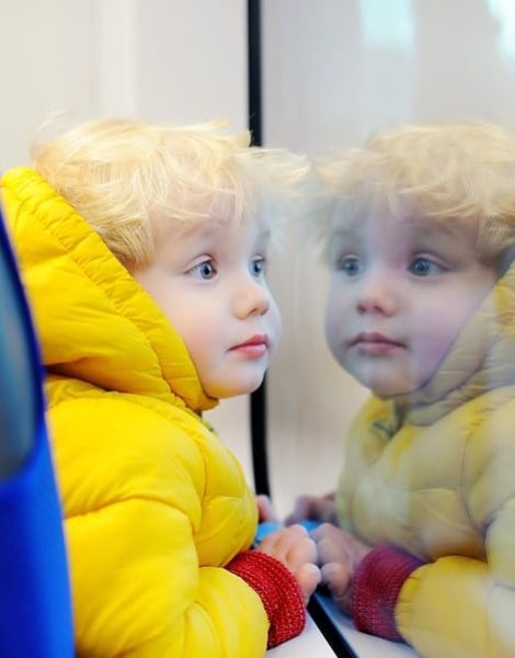 Cute toddler boy looking out train window outside while it moving. Going on vacations and traveling by railway.