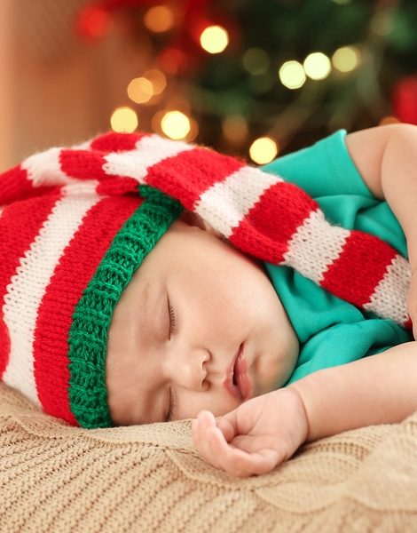 Cute little baby sleeping against blurred Christmas lights background