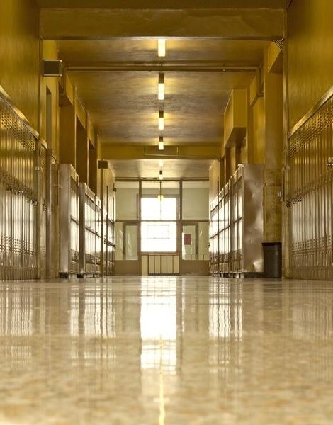 An empty high school corridor with a bright light at the end of the hallway