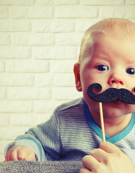 funny baby with a mustache on the brick wall background