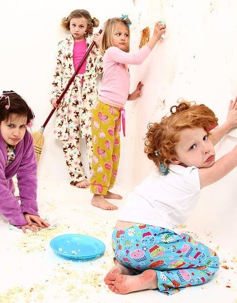 Group of elementary children cleaning up after food fight at slumber party with pizza and popcorn.