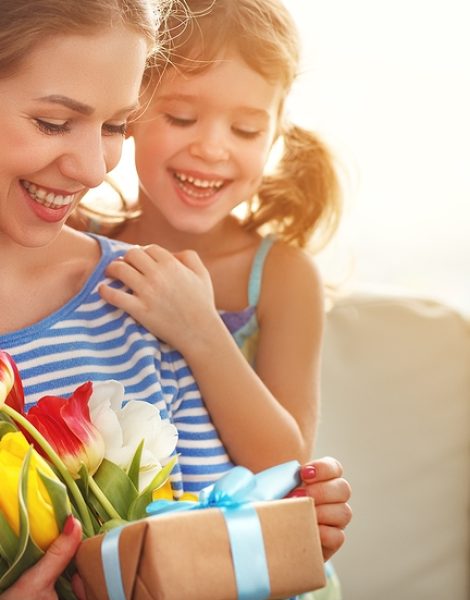 happy mother's day! child daughter congratulates mother and gives a bouquet of flowers to tulips and gift