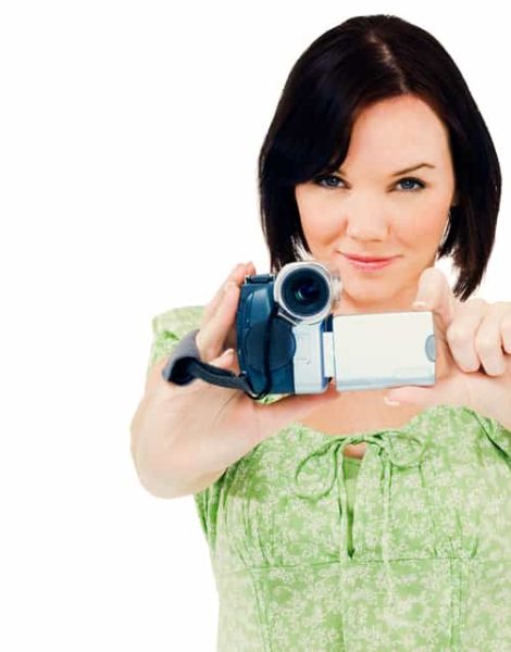 Happy woman holding a home video camera isolated over white