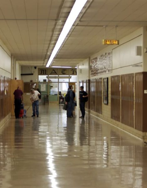 Mostly empty high school hallway with brown lockers