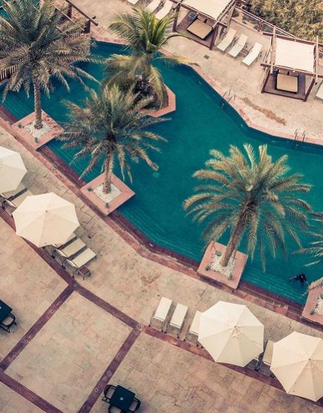 ABU DHABI, UAE - DECEMBER 21:Hotel Poolside with Parasols and Palms in Radisson Blu Hotel. Top view shot on December 21, 2014