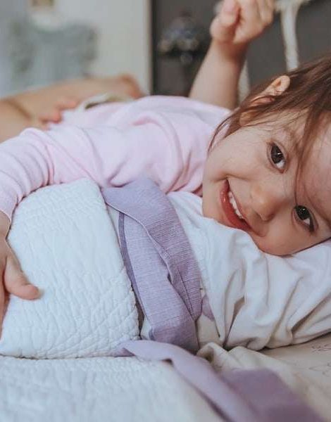 Closeup of adorable little girl smiling lying in the bed in a relaxed morning. Weekend family leisure time concept.