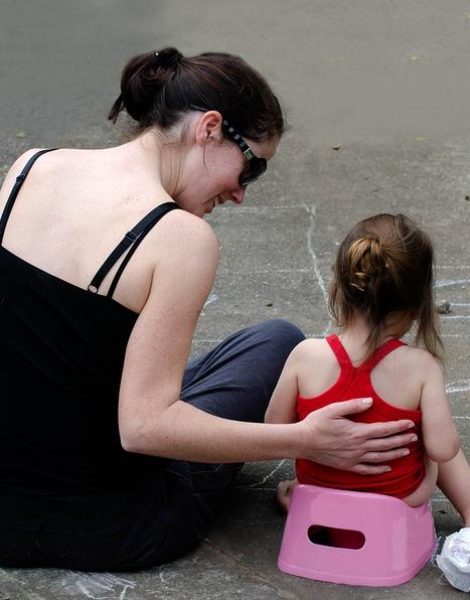 A young mother trains her daughter to use the potty outdoor.