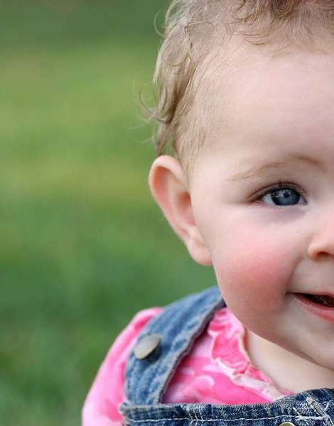 Baby girl's quirky grin with green grass