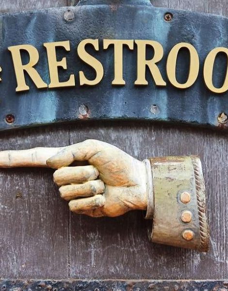 Sign with hand pointing direction to male and female restrooms
