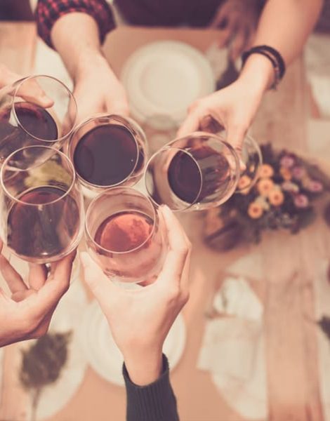 Friends clinking glasses with wine above dinner table