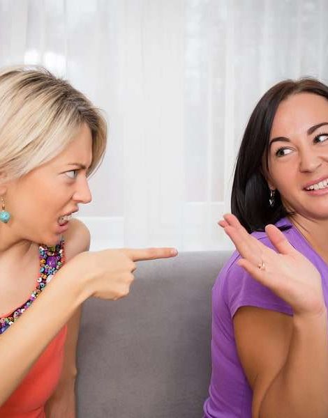 Two women friends arguing sitting on sofa
