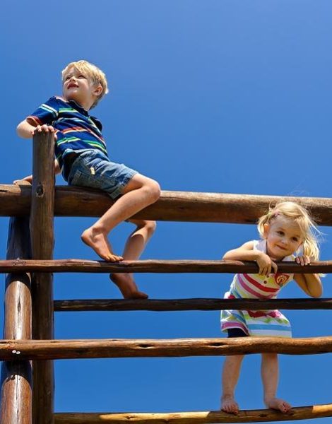 Two young children sitting at the top of playground equipment